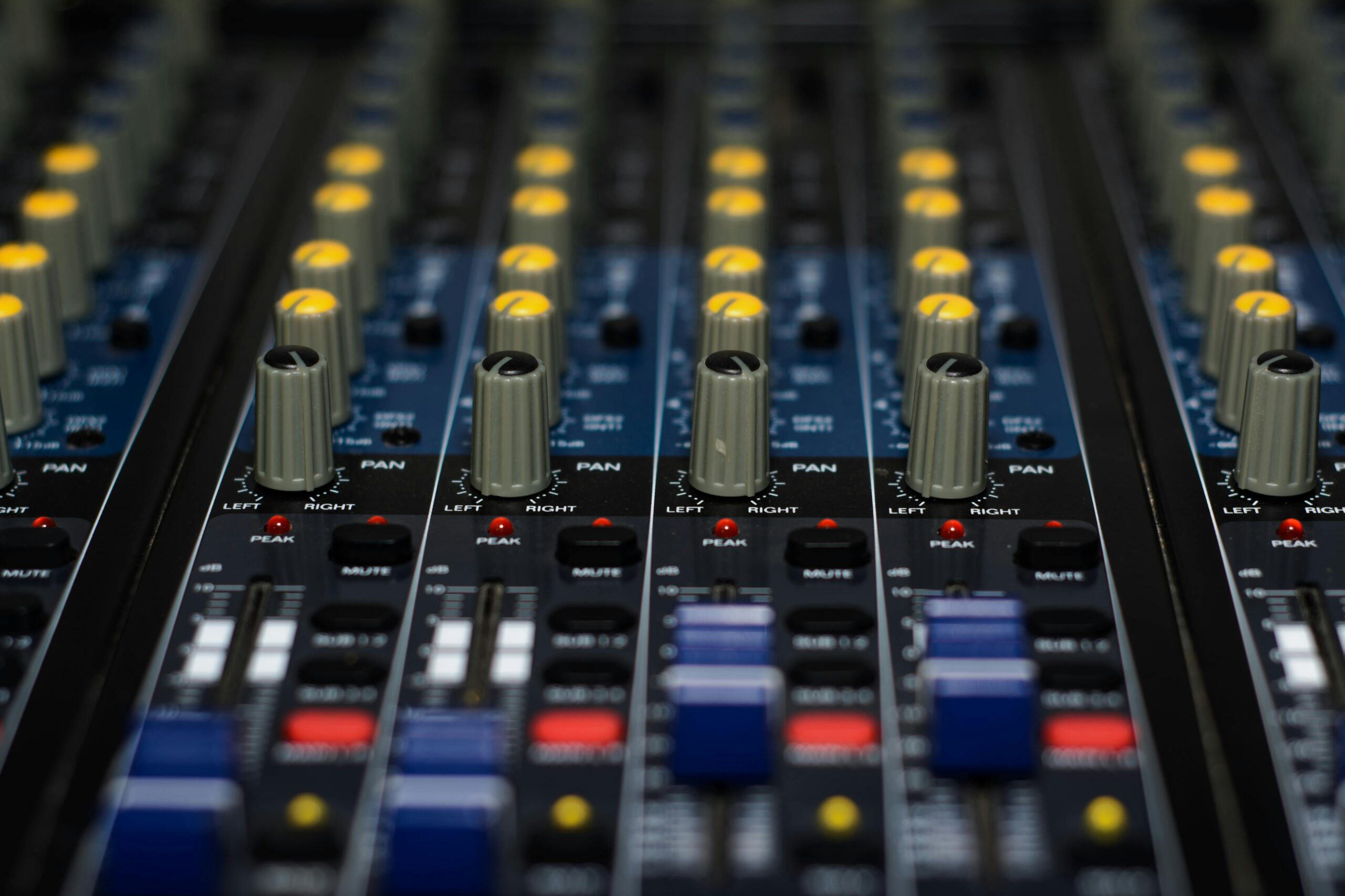 Detailed close-up of audio mixer knobs and buttons used in music production.
